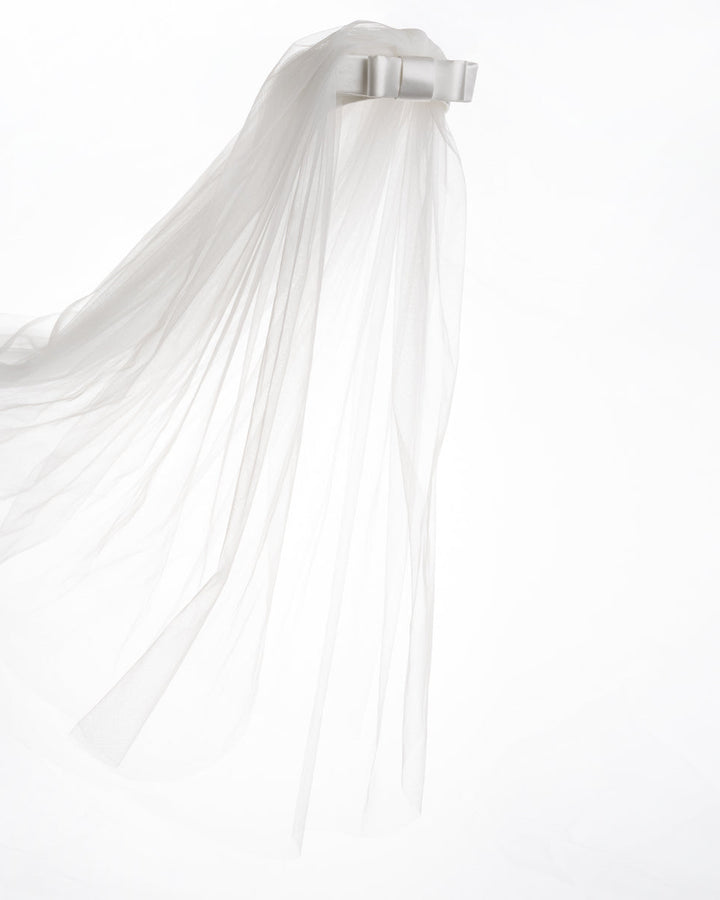 A short white sateen headband decorated with a double layered sateen bow and completed with a two-pieced ghost tulle veil.