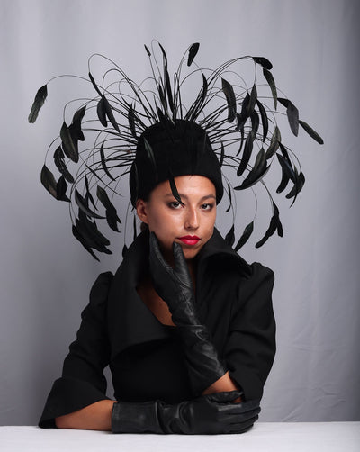 Model is showcasing Tall double pillbox felt base decorated with long Chanel style feathers surrounding the hat