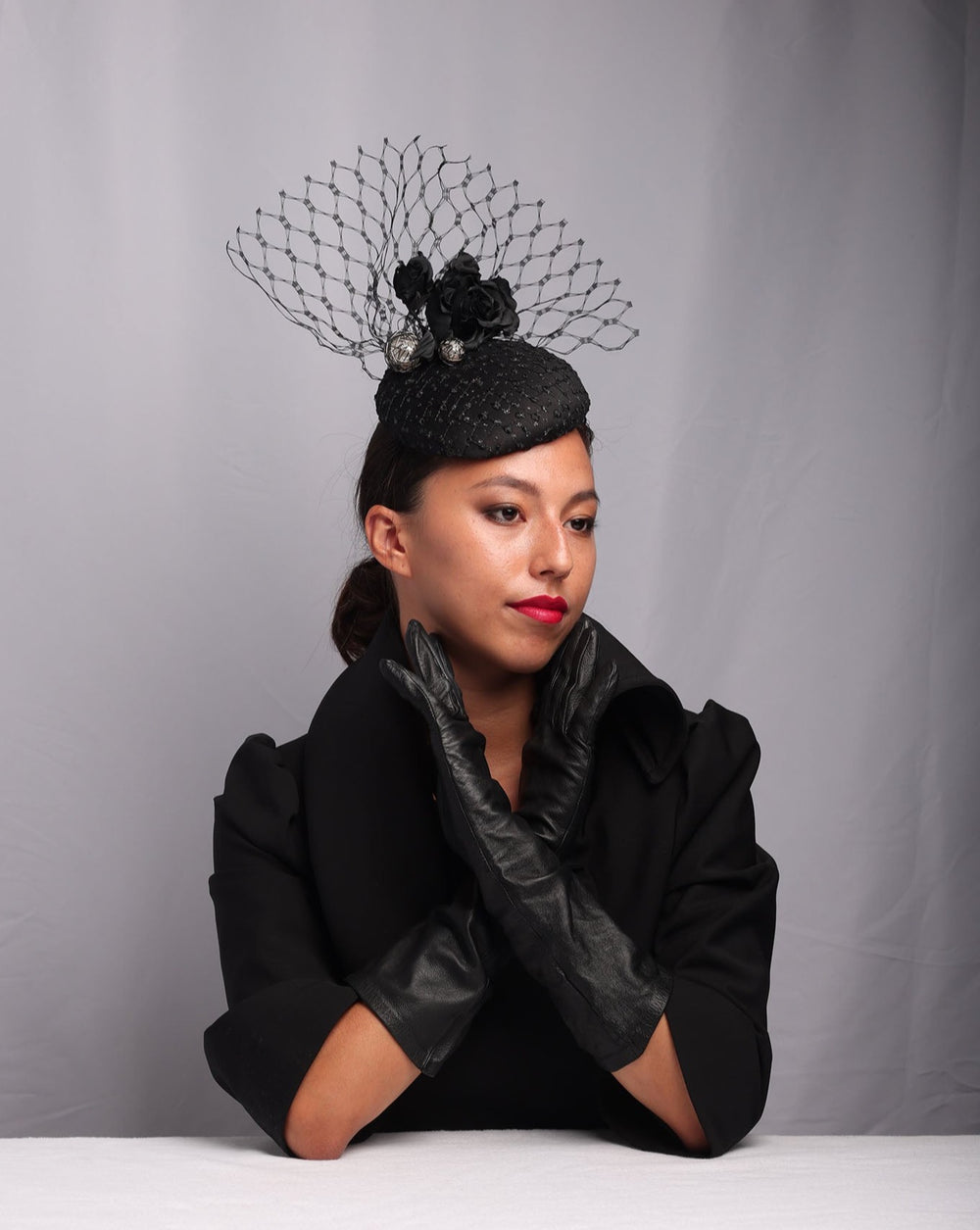 Model showcasing a Medium sateen button shaped fascinator covered with laced tulle with sparkles. The button fascinator is sateen roses, large pearl coloured beads and veil tulle in the back.