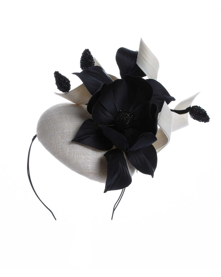 A grade sinamay button shaped white fascinator decorated with white Jinsin Swirls and custom made black American Sateen Cala flower. Designed and made by Merve Bayindir Millinery.
