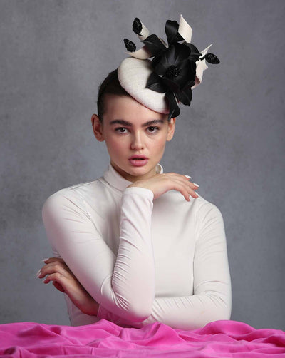 Model is showcasing A grade sinamay button shaped white fascinator decorated with white Jinsin Swirls and custom made black American Sateen Cala flower