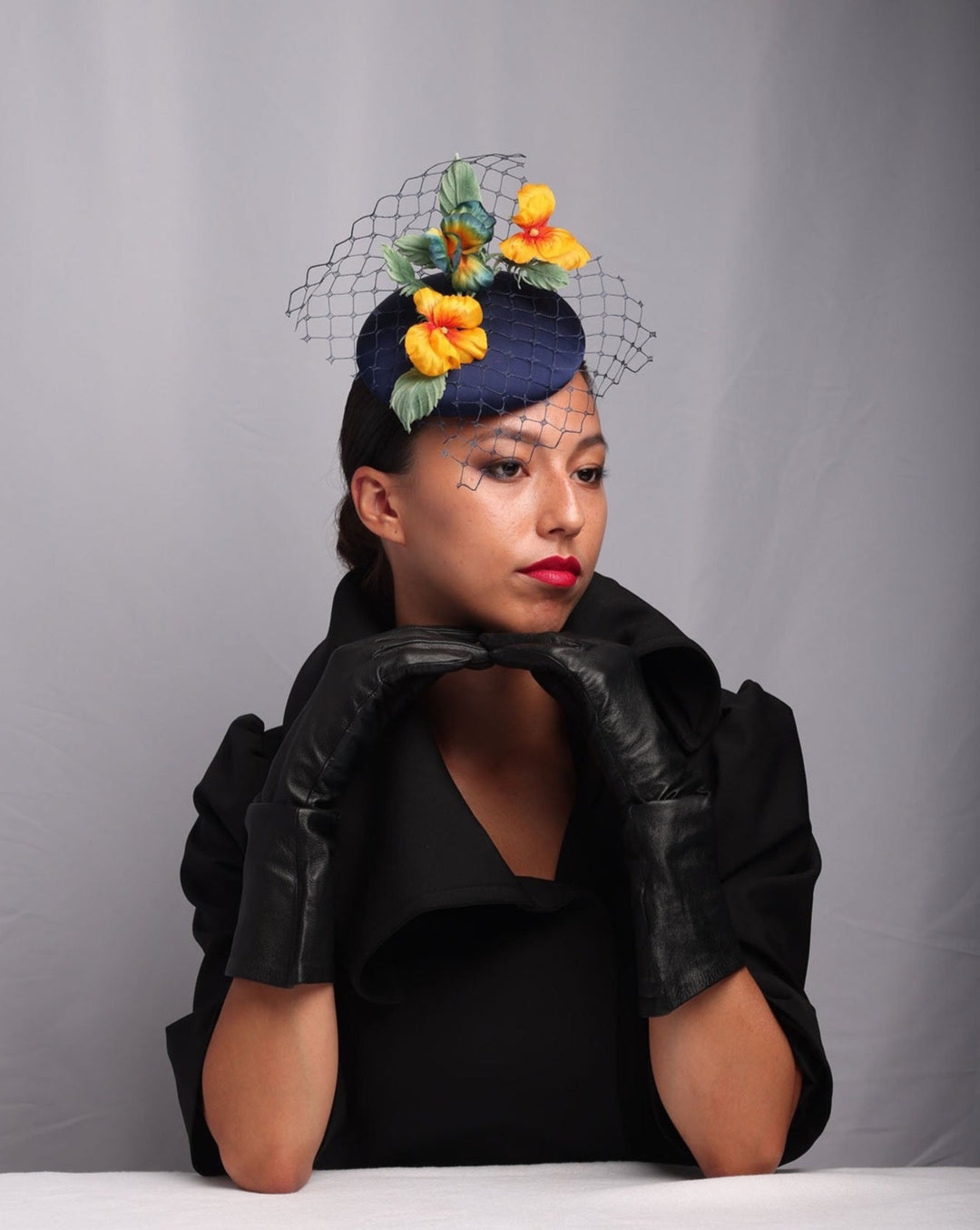 Model is showcasing the right side of the medium sateen button shaped piece decorated with stiffened baby veil and multi colour violets.