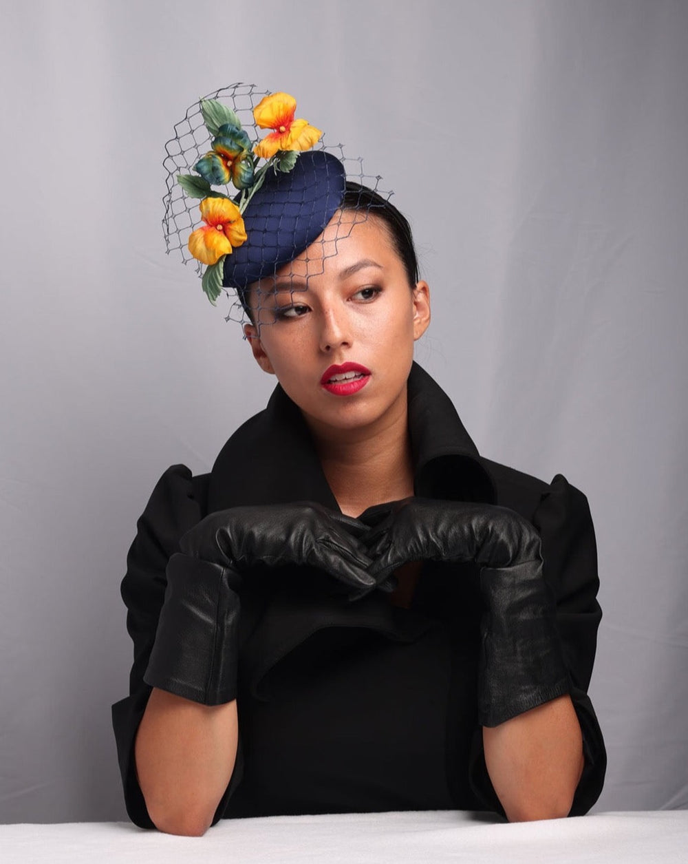 Model is showcasing the front look of Medium sateen button shaped piece decorated with stiffened baby veil and multi colour violets.