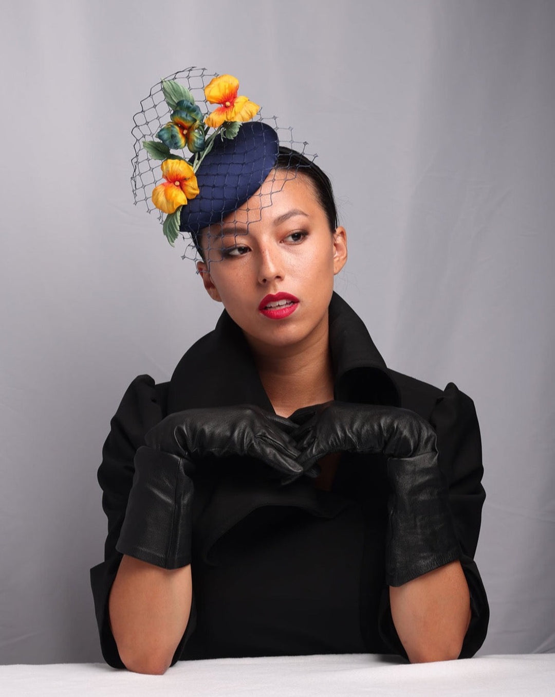 Model is showcasing the front look of Medium sateen button shaped piece decorated with stiffened baby veil and multi colour violets.