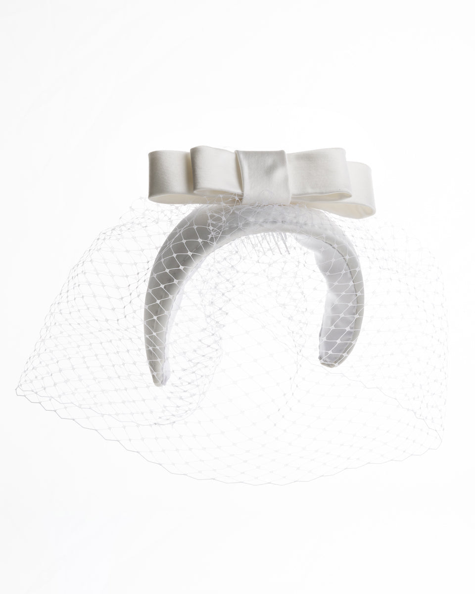 sateen bridal headband decorated with an upright, double layered sateen bow. This minimalistic headpiece is completed with a delicate, round hat veil.