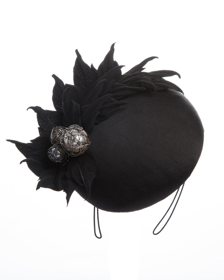 The button style sateen based fascinator decorated with crepe leafs and centred with wire embellished plastic large pearls.