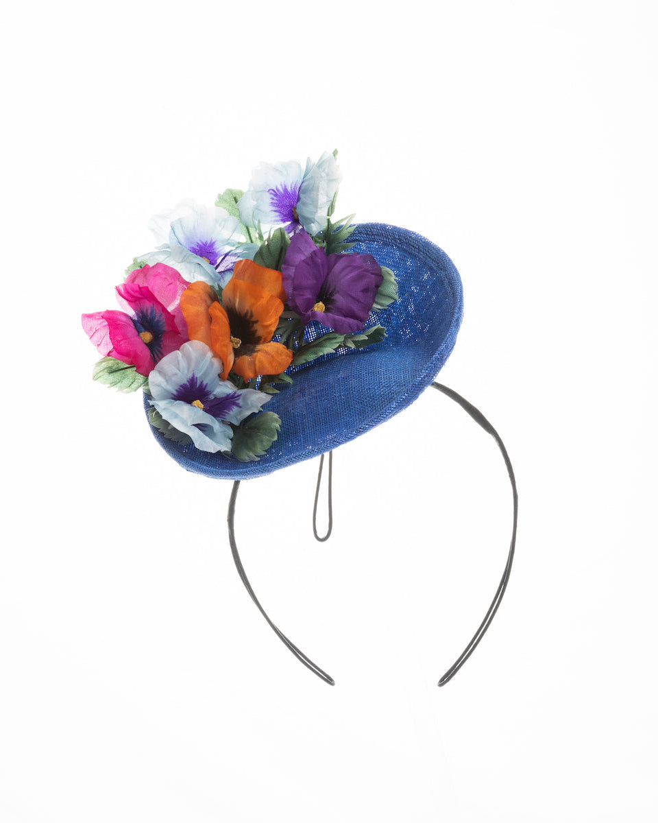 Deep blue saucer style mini fascinator, decorate with different coloured violet flowers. Designed and made by Merve Bayindir Millinery.
