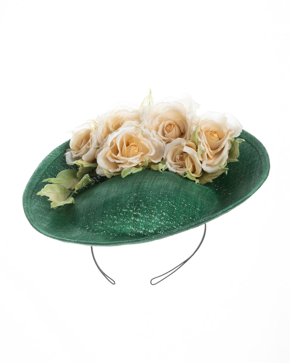 Medium sized emerald green saucer hat decorated with a bouquet on top back side. The bouquet features six flowers in different sizes and shades ranging from light peach to yellow. Designed and made by Merve Bayindir Millinery.