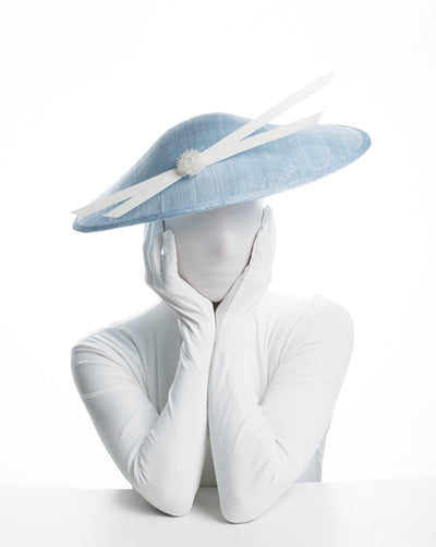 Model is showcasing Light blue sinamay wide brim that features two crossing white buckram lines and cluster white crystal beads. Worn tilted towards the right side of the head